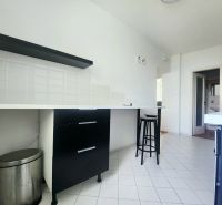 Küche mit weißen Fliesen, schwarzen Möbeln und Barhocker in einer 3-Zimmer-Wohnung.