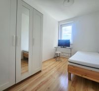 Helles Zimmer mit Bett, weißem Schrank und Fernseher, 3-Zimmer-Wohnung, Boden mit Holzdekor.