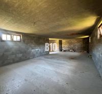 Innenraum einer im Bau befindlichen Hütte mit Betonwänden und -boden.