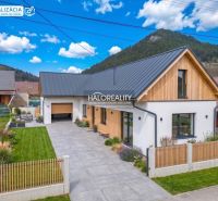 Ein Einfamilienhaus in Stupno mit Garage, gepflegtem Garten und Holzverkleidung an der Fassade.