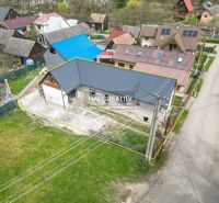 Ein Einfamilienhaus in Stupno mit einem niedrigen blauen Dachprofil, umgeben von benachbarten Gebäuden.