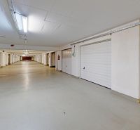 Überdachte Garage mit Sektionaltoren, weißer Decke und Beleuchtung.