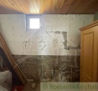 Ein Raum mit einer Holzdecke, einer gemauerten Wand und alten Möbeln in einem Einfamilienhaus.
