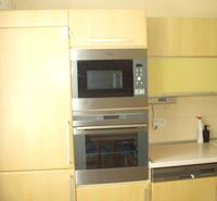 Küche in einer 2-Zimmer-Wohnung mit eingebauten Geräten und hellen Möbeln.