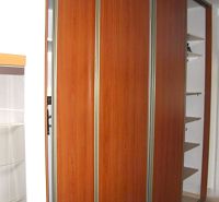 Einbauschrank mit Holzdekor in einer 2-Zimmer-Wohnung, ergänzt durch weiße Wände und Regale.