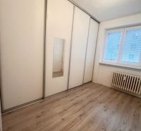 Ein Zimmer in einer 3-Zimmer-Wohnung mit einem weißen Schrank und einem Boden in Holzoptik.