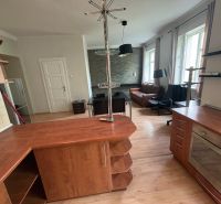 Wohnbereich in einer Zweizimmerwohnung mit Holzboden und Küchenzeile.