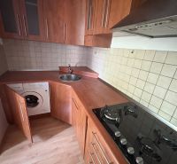Küche in einer 2-Zimmer-Wohnung mit Holzboden und eingebauten Geräten.