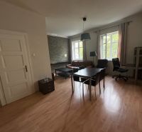 Innenraum einer 2-Zimmer-Wohnung mit Holzboden, Tisch und Stuhl.