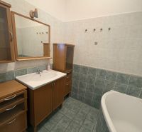 Badezimmer in einer 2-Zimmer-Wohnung mit Badewanne und Holzschrank.