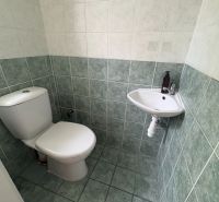 Toilette mit Fliesen und kleinem Waschbecken in einer Zweizimmerwohnung.