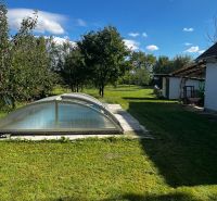 Ein Einfamilienhaus im Čalovecká-Garten mit einem Pool unter einer gewölbten Abdeckung und einer Rasenfläche.