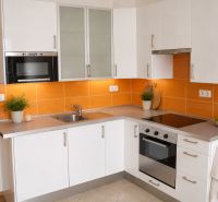 Eine Küche mit weißen Schränken, eingebautem Ofen und orangefarbenen Fliesen in einem Einzimmerapartment.