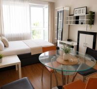 Innenraum eines Einzimmerapartments mit Bett, Tisch, Glastisch und Schränken, Boden mit Holzdekor.