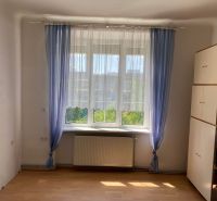 Ein Zimmer mit einem Schrank, Fenster und Vorhängen in einer 2-Zimmer-Wohnung, Boden mit Holzdekor.