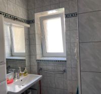 Badezimmer in einer 2-Zimmer-Wohnung mit Fliesen, Waschbecken und Fenster.