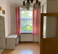 Ein Zimmer mit Holzboden und rosa Vorhängen in einer Zweizimmerwohnung.