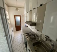 Küche in einer 2-Zimmer-Wohnung mit weißen Schränken und Fliesenboden.