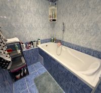 Badezimmer mit Badewanne und blauen Fliesen in einer 2-Zimmer-Wohnung.
