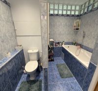 Badezimmer in einer 2-Zimmer-Wohnung mit Badewanne und blauen Fliesen.