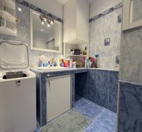 Badezimmer in einer 2-Zimmer-Wohnung mit Waschmaschine und blauen Fliesen.