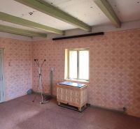Ein Zimmer in einem Einfamilienhaus mit Retro-Tapeten, einem Heizkörper und einem Boden mit Holzdekor.
