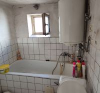 Badezimmer in einem Einfamilienhaus mit Fliesen, Badewanne und Boiler.