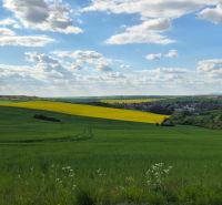 Das Dorf bietet einen atemberaubenden Blick auf die grüne Landschaft mit blauem Himmel und Wolken.