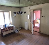 Ein Zimmer in einem Einfamilienhaus mit einem Holzboden, älteren Möbeln und einem Fenster.
