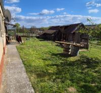 Ein Einfamilienhaus in Dedinka mit einem großen Garten, viel Grün und einem älteren Gebäude im Hintergrund.