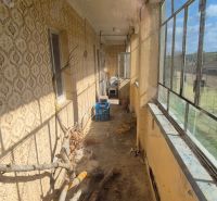 Im Einfamilienhaus befindet sich eine geschlossene Veranda mit älteren Fenstern und einer gemusterten Wand.