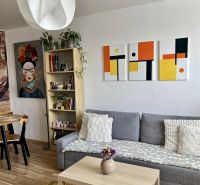 Wohnzimmer in einer 2-Zimmer-Wohnung mit Sofa, Tisch und Holzboden.