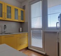 Küche mit gelben Schränken in einer 2-Zimmer-Wohnung, Boden mit Holzdekor.