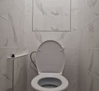 Toilette mit Keramikfliesen in einer 2-Zimmer-Wohnung.