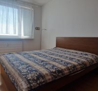 Schlafzimmer mit einem Bett und einem Boden in Holzoptik in einer 2-Zimmer-Wohnung.