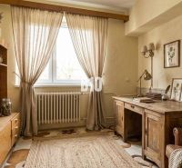 Innenraum eines Einfamilienhauses mit Holzmöbeln, Teppich und Wanddekorationen.