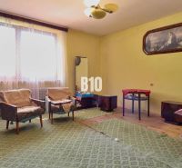 Ein Zimmer in einem Einfamilienhaus mit Sesseln, einem Tisch und Teppichboden.