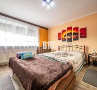 Schlafzimmer im Einfamilienhaus mit Bett, Holzboden und orangefarbenen Wänden.