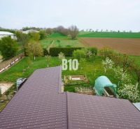Ein Einfamilienhaus in Lukáčovce mit einem weitläufigen Garten und umliegenden Feldern.