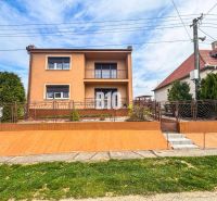 Ein Einfamilienhaus in Lukáčovce mit Garten und erhöhtem Eingang, umgeben von einem Zaun.