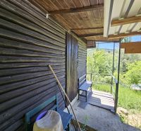 Eine Hütte in Budatín mit Holzverkleidung, Terrasse und Blick auf den grünen Garten.