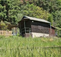 Eine Hütte in Budatín am Waldrand, umgeben von Grün und einem Holzzaun.