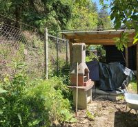 Ein Gartenkamin neben einer Hütte auf einem Waldweg in Budatín, umgeben von Grün.