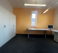 Ein Büro mit Möbeln, einem Computer und Schränken auf einem hellen Boden.