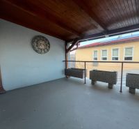 Überdachte Terrasse mit Uhren und Pflanzgefäßen in den Produktionsräumen.