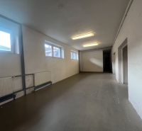 Langer Raum mit weißen Wänden, Fenstern und gusseisernen Heizkörpern in Lagern und Hallen.
