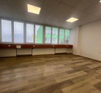 Ein leeres Büro mit einem Holzboden und großen Fenstern.