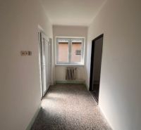Das Innere eines Einfamilienhauses mit weißen Wänden, einem Heizkörper und einem großen Fenster.
