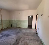 Ein Zimmer in einem Einfamilienhaus mit unfertigem Boden und grünen Fliesen.