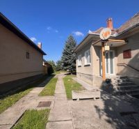 Das Äußere eines Einfamilienhauses in Vrakúň, Gehweg, Rasen, Baum und blauer Himmel.
